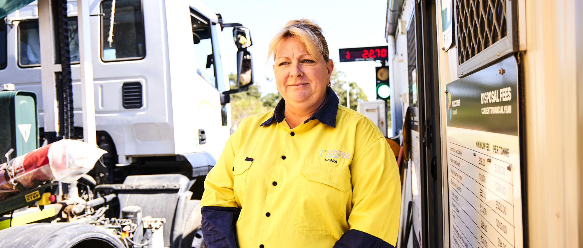 header-6 Male staff wearing protective eye and ear wear, standing in front of a bottle recycling machine