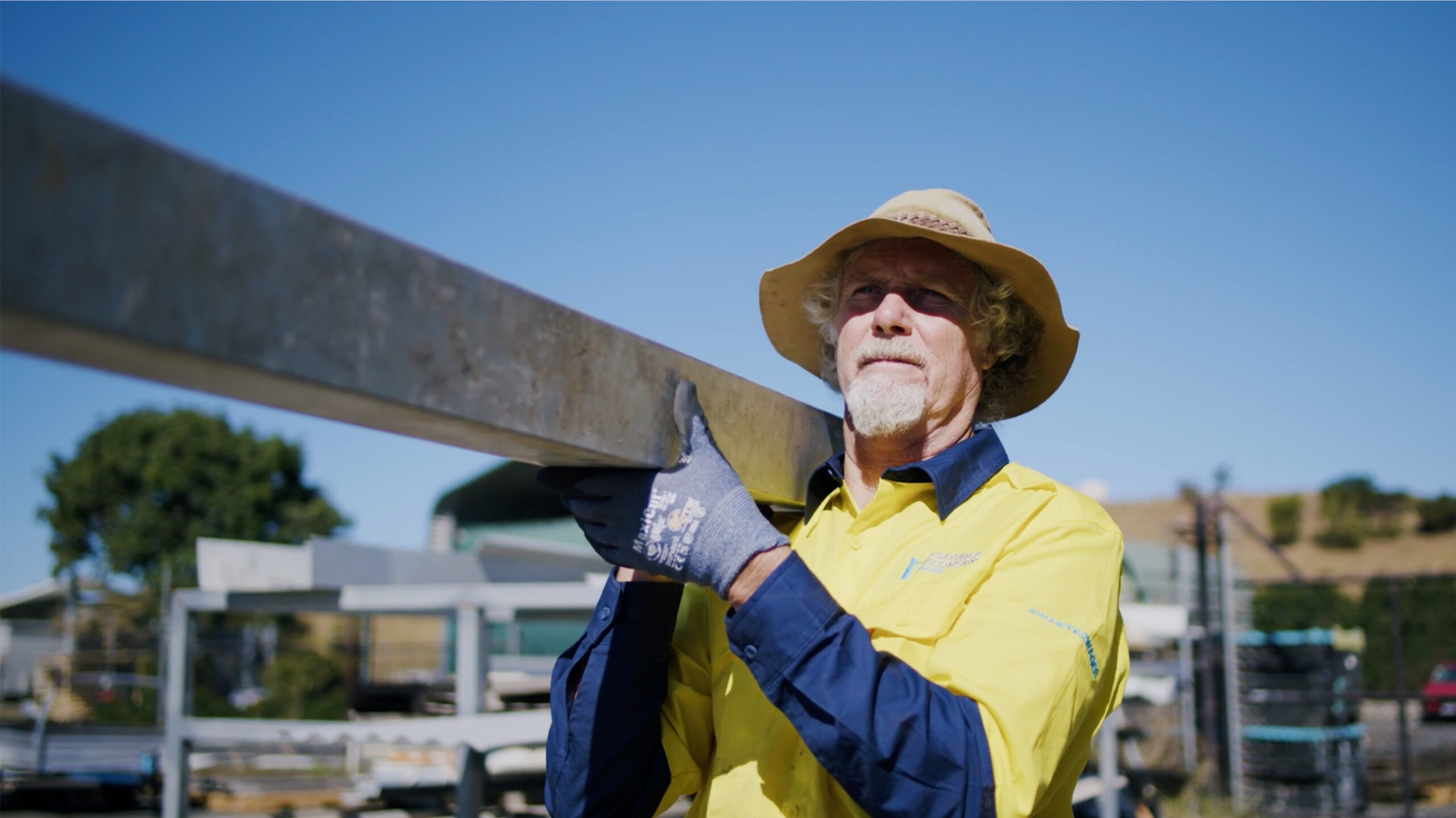 Male staff wearing protective eye and ear wear, standing in front of a bottle recycling machine